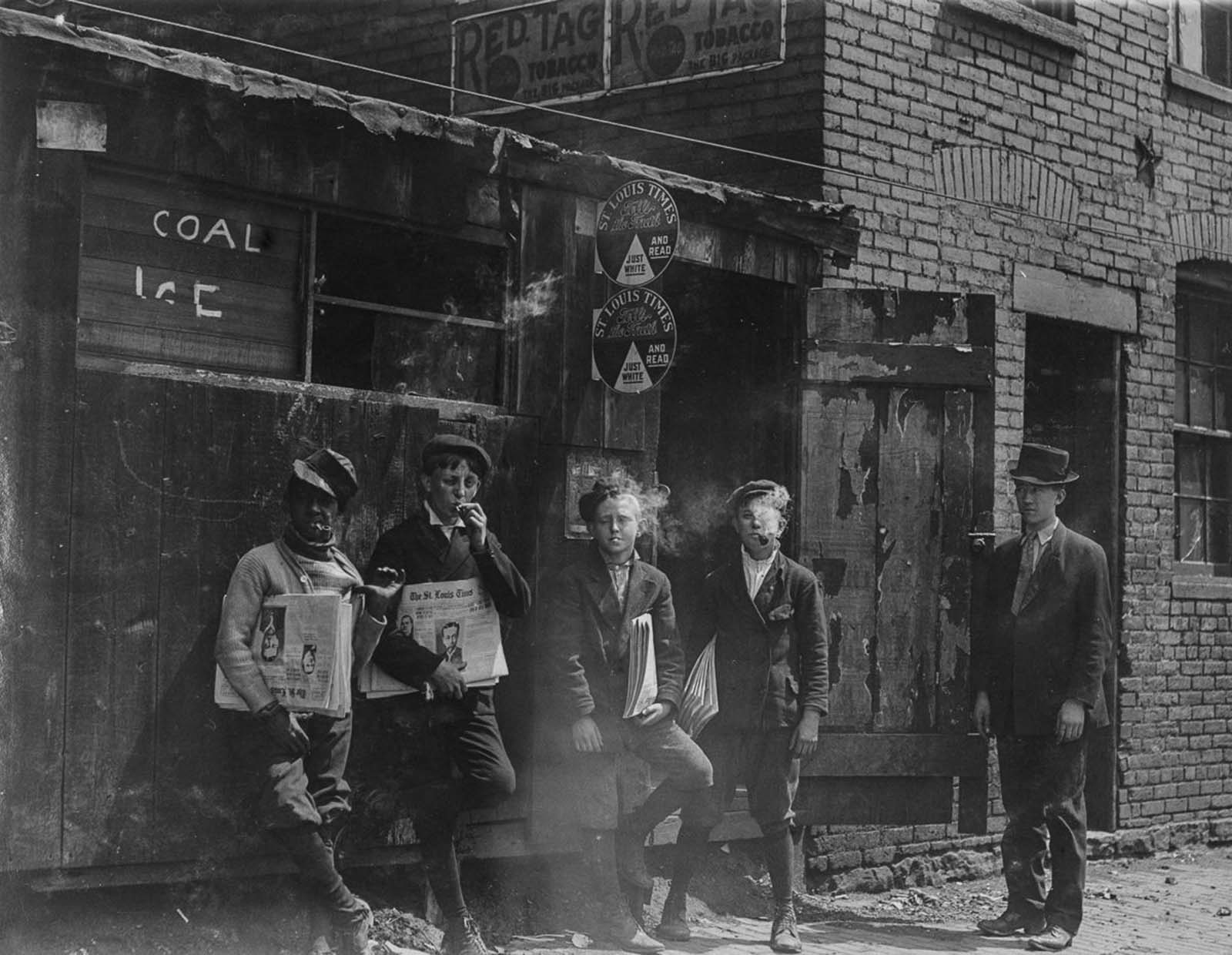 Lewis Hine photograph of newsboys smoking outside a storefront, holding copies of The St. Louis Times